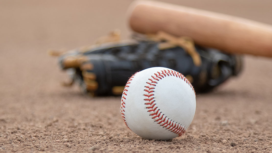 The image shows a baseball on a field with a bat and glove nearby.