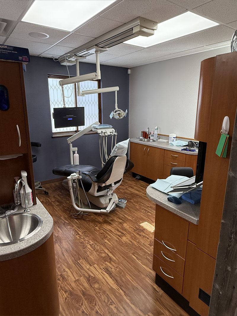 The image shows an interior view of a dental office with a modern setup, including dental chairs, equipment, and a reception area.