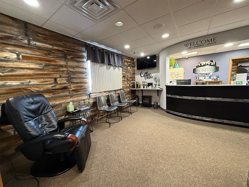 An interior view of a waiting room with a rustic wall design, a chair, and a reception desk.