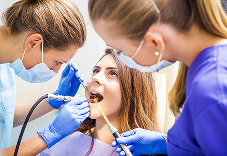 The image shows dental professionals performing oral care procedures on a patient at a dental clinic.