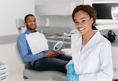 Dental hygienist and dentist in a professional setting, smiling at camera.